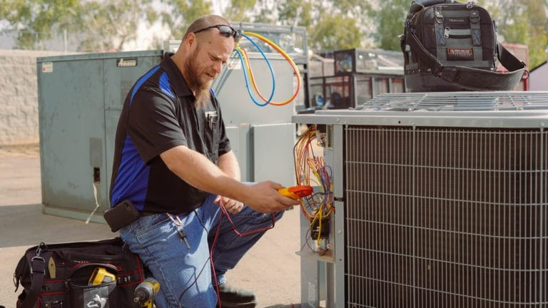 Technician performing AC maintenance service on a residential unit