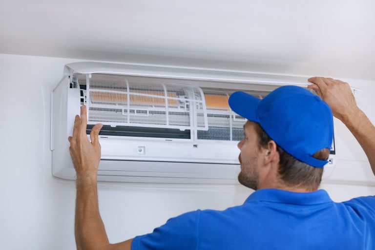 Technician performing HVAC maintenance on an air conditioning unit